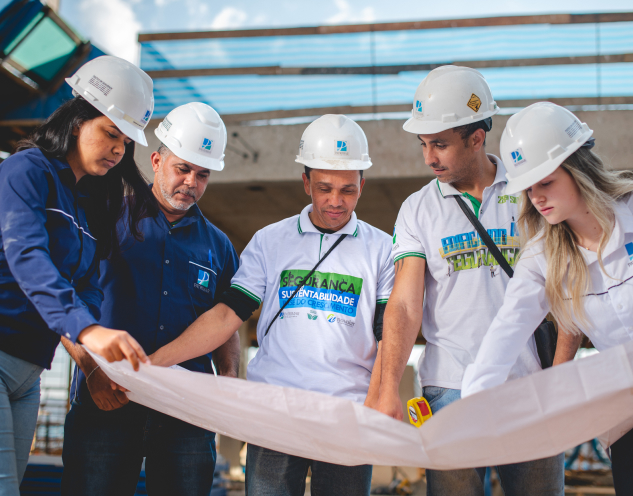 Equipe de segurança e sustentabilidade em construção da Patrimar revisando plantas no canteiro de obra.